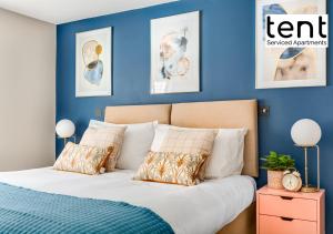 a bedroom with blue walls and a bed with pillows at COZY 2 BED Apt Steps to town centre by Tent Serviced Apartments Egham with Free Parking and Wifi in Egham