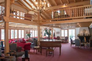 a large room with a piano and chairs at Waldhotel Doldenhorn in Kandersteg