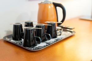 a tray with black cups on a table with a tea kettle at Hotel Tuulonen in Tuulos