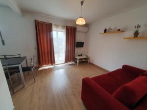 uma sala de estar com um sofá vermelho e uma mesa em Pretty flat with terrace, air cond, free parking em Porto