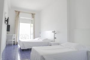 biała sypialnia z 2 łóżkami i oknem w obiekcie Hotel Venere Azzurra w mieście Lerici