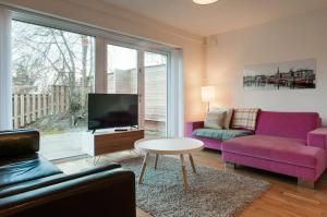 sala de estar con muebles de color púrpura y TV en townhouse on Arlanda Stockholm metro line - easy checkin en Sollentuna