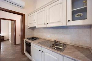 - une cuisine avec des placards blancs et un évier dans l'établissement Messalina Agriturismo La Scuderia, à Molino Nuovo