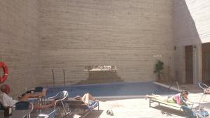 a group of people sitting in chairs in a swimming pool at Hostal Rural San Andrés in Torres del Río