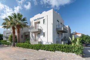 a white building with a palm tree in front of it at Bella Vista Hotel "by Checkin" in Hersonissos