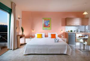 a bedroom with a large white bed and a kitchen at Bella Vista Hotel "by Checkin" in Hersonissos
