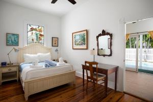 a bedroom with a bed and a desk and a mirror at The Conch House Heritage Inn in Key West