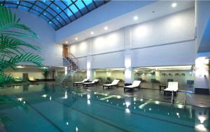 a swimming pool with chairs and a staircase in a building at Hotel New Otani Chang Fu Gong in Beijing