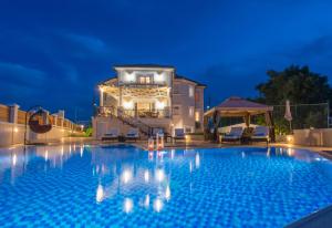 Frido Luxury Villa with Jacuzzi في Akrotiri: مسبح امام بيت بالليل