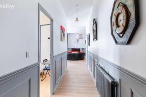 un couloir avec une horloge sur le mur dans l'établissement Cauquilha SPACIEUX APPARTEMENT BOURGEOIS EN CENTRE VILLE, à Béziers