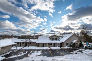 a house covered in snow in a parking lot at Boyne City Motel in Boyne City