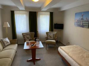 ein Hotelzimmer mit einer Couch, Stühlen und einem Tisch in der Unterkunft Hotel Pension Gelpkes Mühle in Bad Sachsa