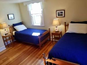 a bedroom with two beds with blue sheets and a window at Sunny Home B&B in Charlottetown