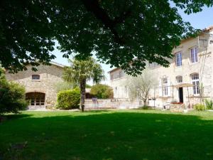 - un grand bâtiment en pierre avec une pelouse verdoyante devant dans l'établissement ferme st pierre suite, piscine, clim, repas, cheminée, à Chabeuil