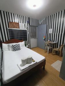 a bedroom with a white bed and a table with a chair at DJCI Apartelle Small Rooms in Cabanatuan