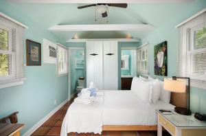 Un dormitorio con una cama blanca y paredes azules. en The Conch House Heritage Inn, en Key West