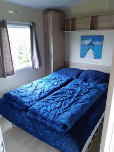a bed with a blue comforter in a bedroom at RBR 244 - Beach Resort Kamperland in Kamperland