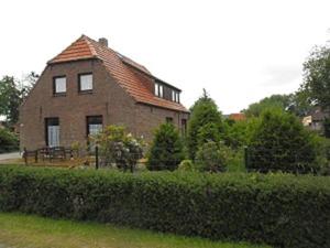 a brick house with a hedge in front of it at Ferienhaus 3119 in Tossens in Butjadingen OT Tossens