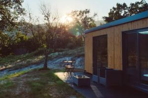 a picnic table next to a building with the sun setting at Casa d' Além Turismo e Natureza - Refúgio do Valouto in Torneiro