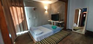 a small bedroom with a bed and a television at Suítes no paraíso da Ilhabela in Ilhabela