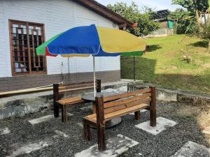 un banco de madera con una mesa con una sombrilla colorida en Casita familiar de campo condina, en Pereira