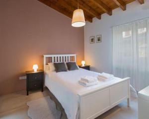 sypialnia z dużym białym łóżkiem z 2 stolikami nocnymi w obiekcie Del Conte w mieście Kalopanajotis