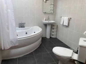 a bathroom with a tub and a toilet and a sink at Charlies Lane Apartment in Donegal