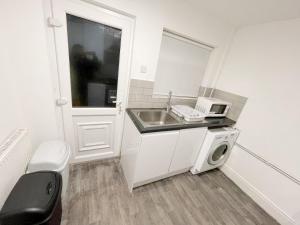 a small kitchen with a sink and a microwave at New Brighton Flat in Wallasey