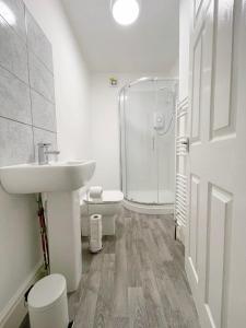 a white bathroom with a sink and a shower at New Brighton Flat in Wallasey