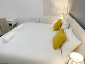 uma cama branca com almofadas amarelas num quarto em New Brighton Flat em Wallasey