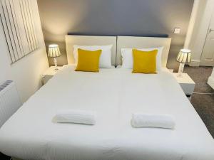 a large white bed with yellow pillows in a bedroom at New Brighton Flat in Wallasey