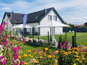 una casa blanca con flores delante en Zatoka Wypoczynku Grzybowo - Apartamenty dwupoziomowe en Grzybowo