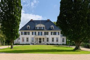 a large white house with a large yard at Hotel Gut Immenhof in Malente
