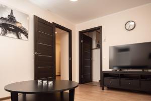 a living room with a table and a flat screen tv at Crown Apartment in Ukmergė