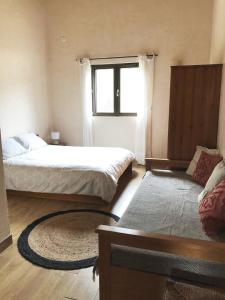 a bedroom with two beds and a window and a rug at Villa familiale entre mer et montagne Corse in Soccia