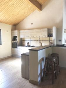 a large kitchen with a large counter and stools at Villa familiale entre mer et montagne Corse in Soccia