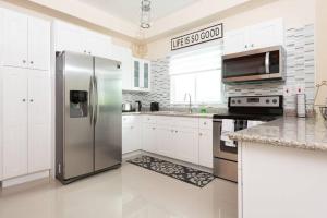 una cocina con nevera de acero inoxidable y armarios blancos en Confluence@Surbiton, en Kingston