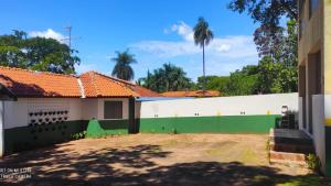 a building with a green and white wall and palm trees at Pousada Recanto das Maritacas in Brotas