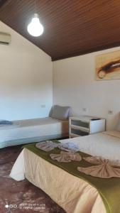 a bedroom with two beds and a table and a lamp at Pousada Recanto das Maritacas in Brotas