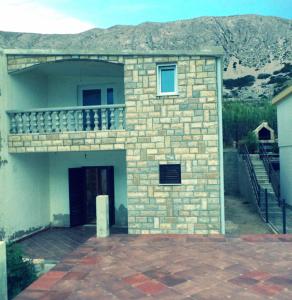 a brick building with a balcony on top of it at Apartments Radnić in Pag