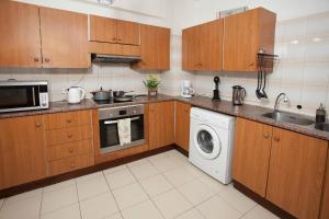 eine Küche mit Holzschränken und einer Waschmaschine in der Unterkunft Nefeli Sea Side, Boutique Apartment in Limassol