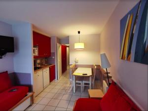 a living room and kitchen with a red couch and a table at Great condo between golf course and beach in Moliets-et-Maa