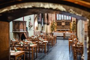 an empty restaurant with wooden tables and chairs at Hotel Monasterium PoortAckere in Ghent