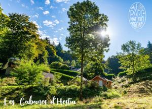 a view of a farm with the sun shining through trees at Les Cabanes d'Hestia in La Salvetat