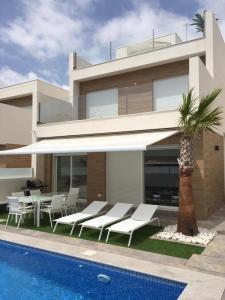 a house with a swimming pool next to a palm tree at Palmeras Gold - Moderne villa (6p) met solarium/privézwembad in San Pedro del Pinatar