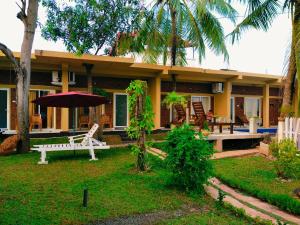 a house with a bench and an umbrella in front of it at Petit Guest House in Negombo