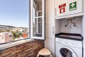 uma lavandaria com uma máquina de lavar roupa e uma janela em Akicity Campolide Apollo em Lisboa