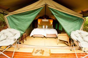 a bedroom in a tent with a bed and chairs at Amafu Forest Lodge in Hoedspruit