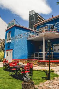 un edificio azul con sillas rojas y una mesa en Blau Hostel en Villa Carlos Paz