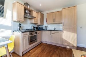 cocina con armarios de madera y mesa en One Bedroom Flat in Bush Hill Park, en Enfield